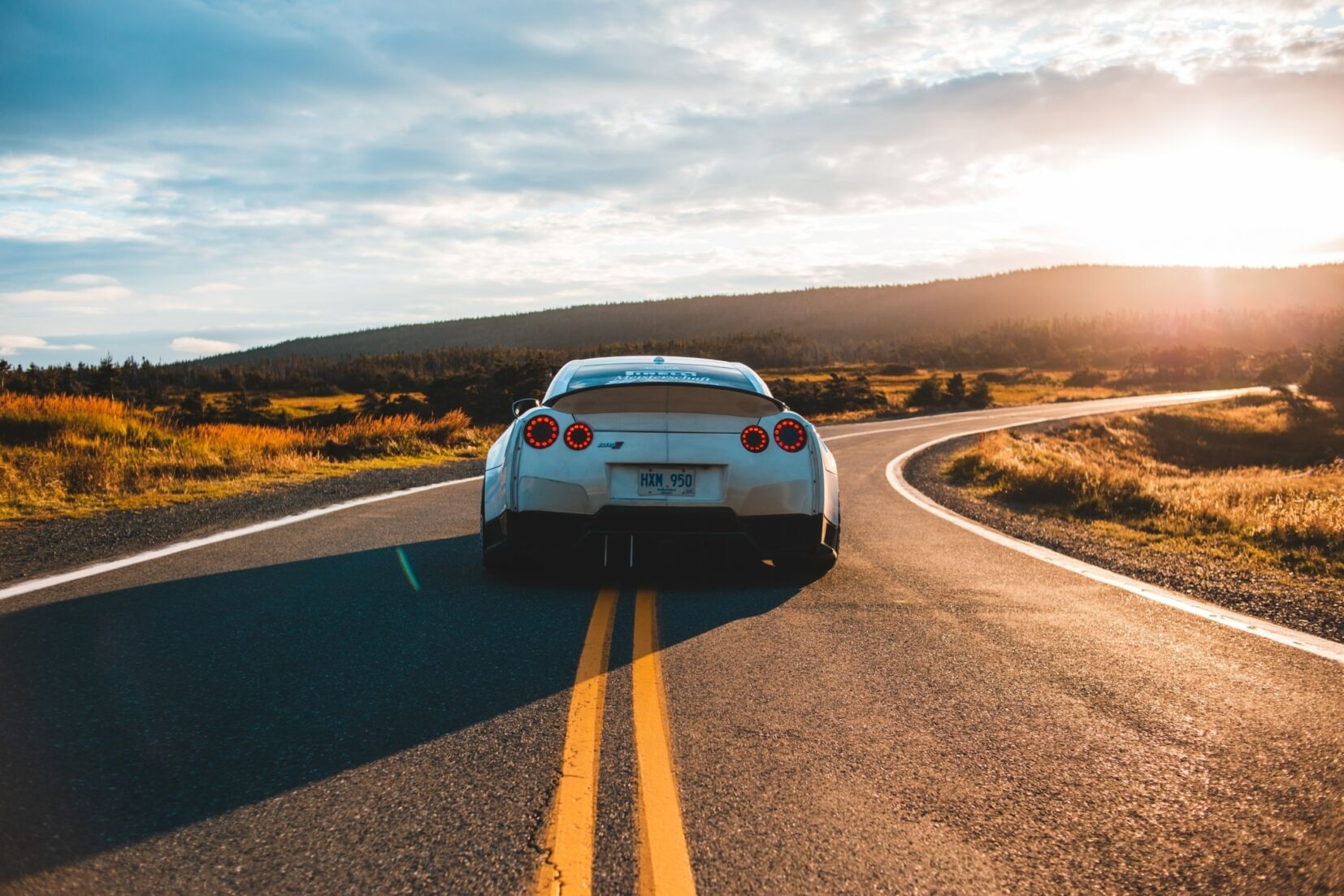 A car travelling down a country road at sunset
