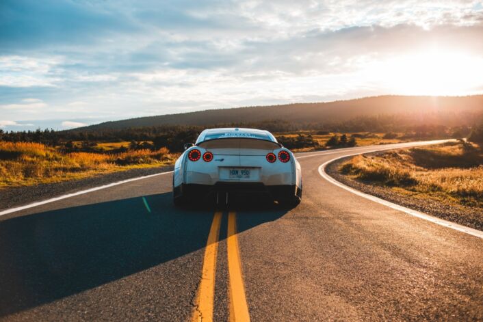 A car travelling down a country road at sunset